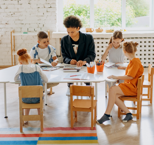 Teacher guiding a small group of elementary students during a reading session at a classroom table